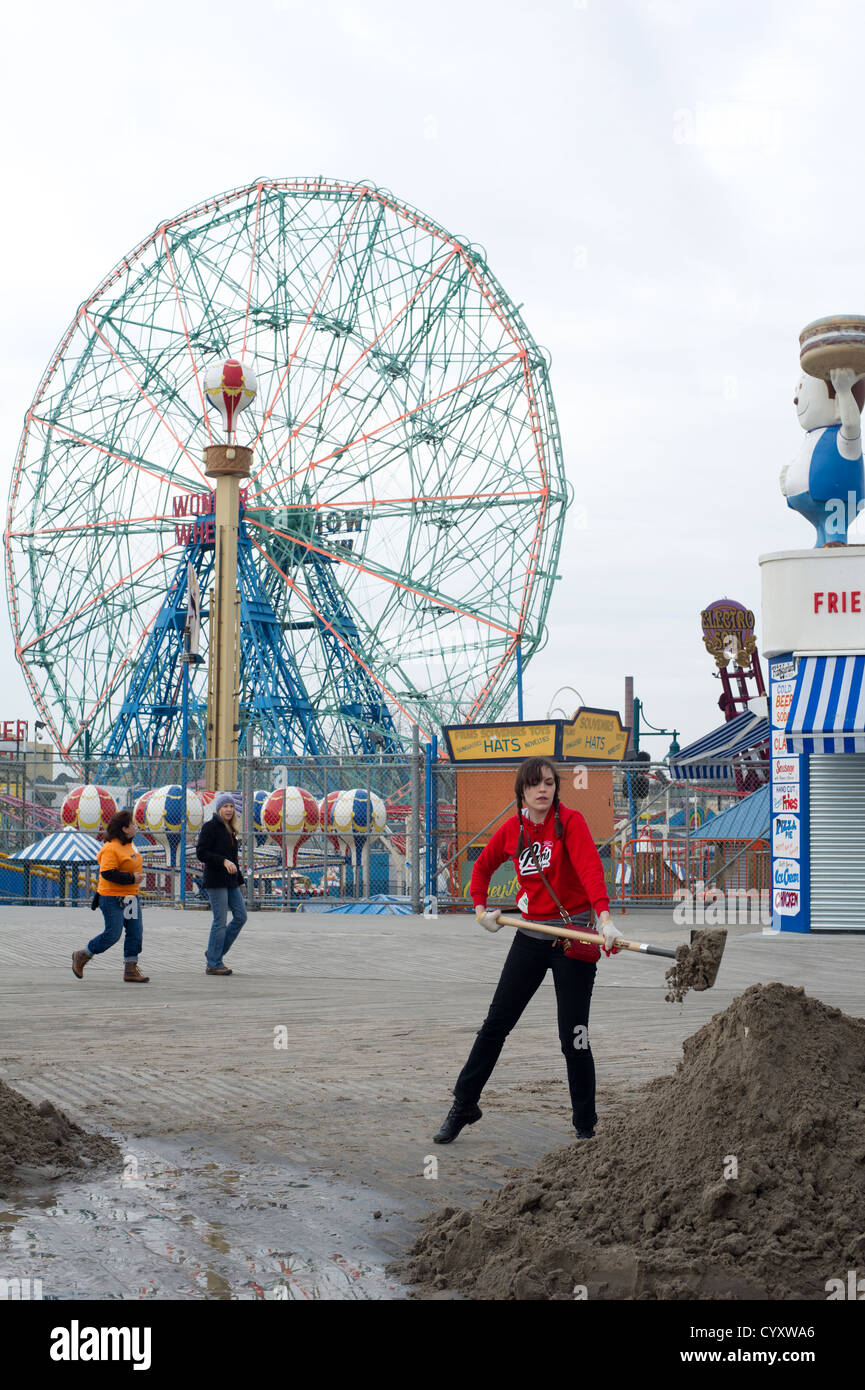 Volontari pulire eventuali detriti e sabbia depositato dall' uragano Sandy dalla spiaggia e dal lungomare Foto Stock