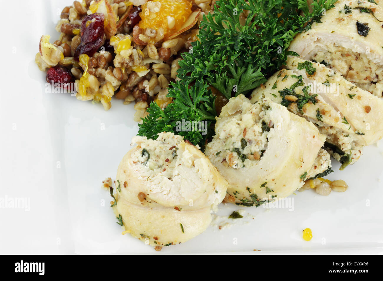 Involtini di pollo ripieni di spinaci e pasta di mandorle servita con pilaf con grani interi, i dadi e la frutta secca. Foto Stock