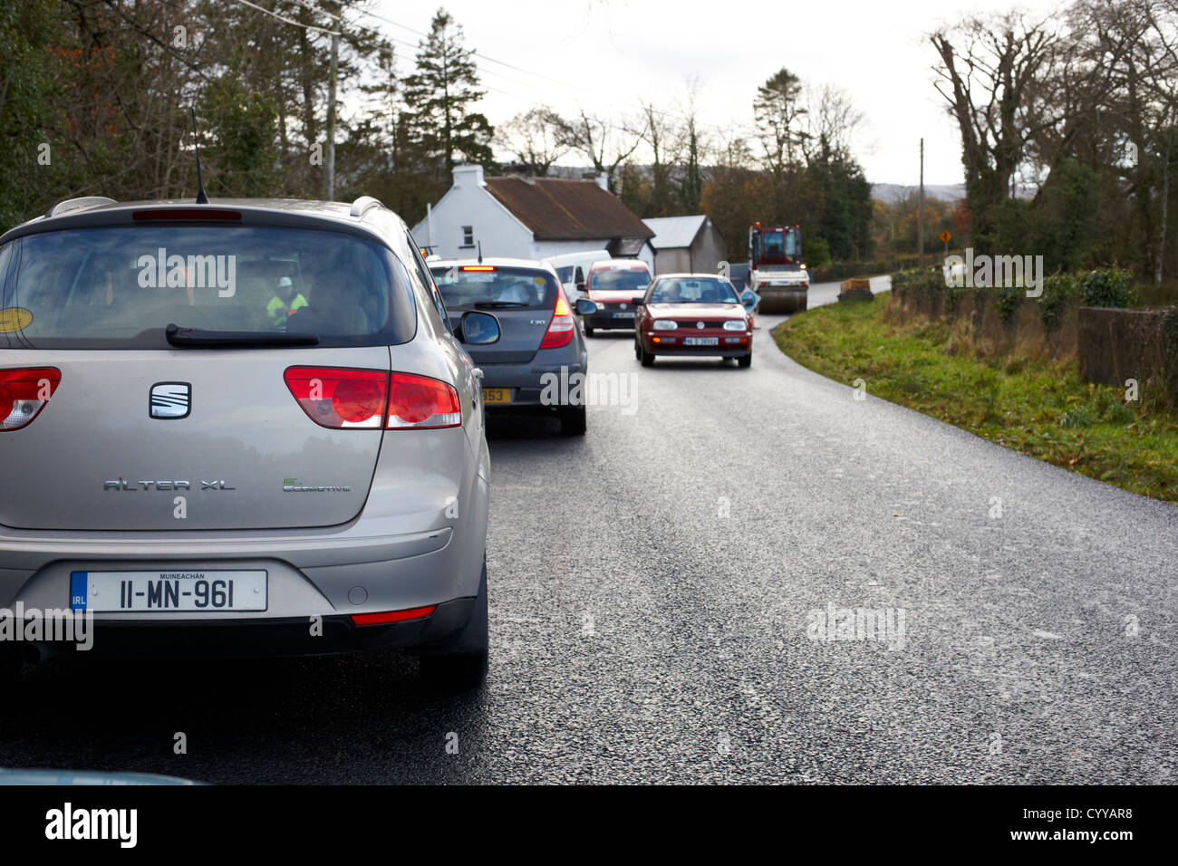 Automobili in attesa nel traffico a causa di rifacimento della pavimentazione stradale sulla strada di un paese in Repubblica di Irlanda Foto Stock