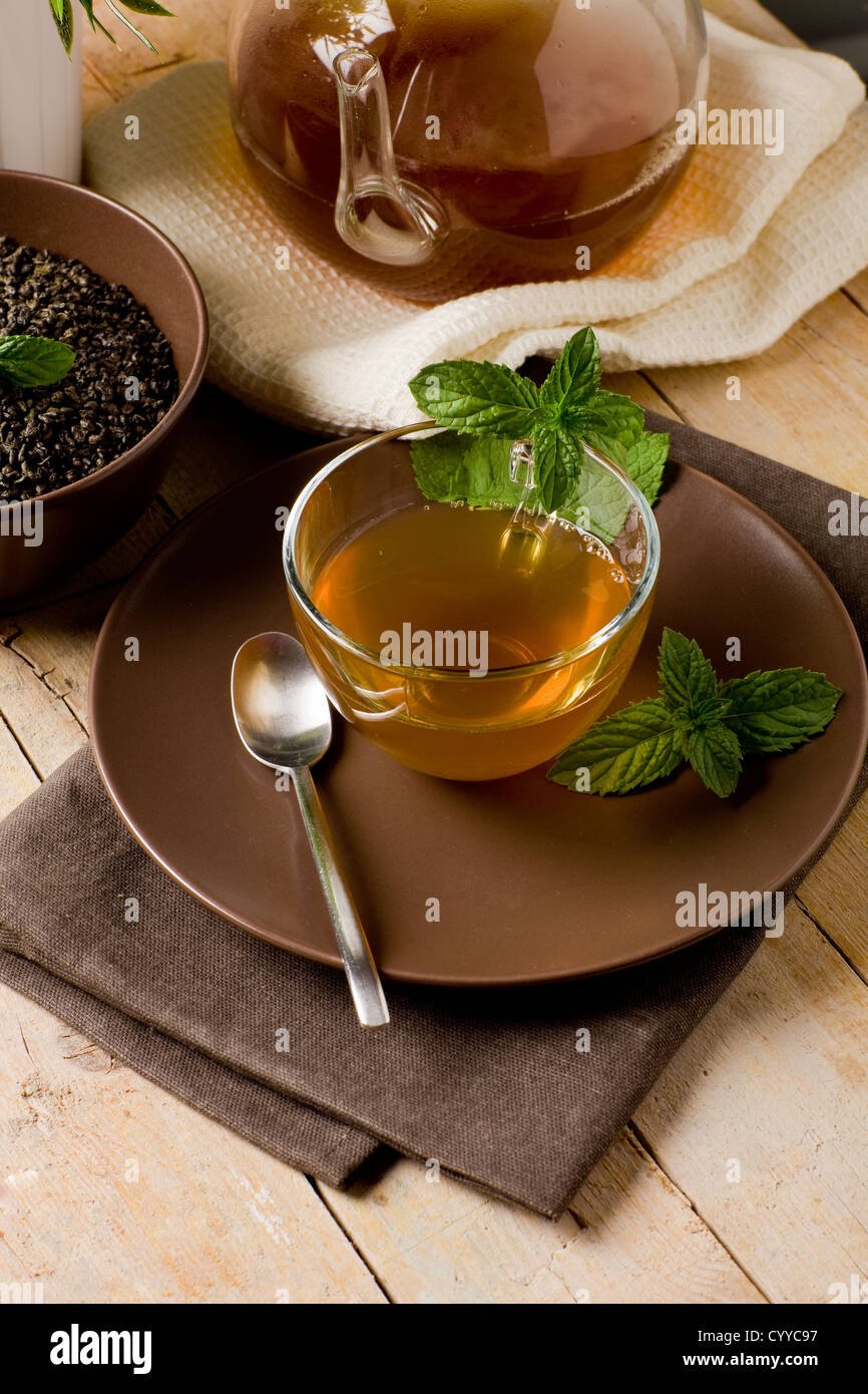 Foto di verde delizioso tè alla menta in coppa di vetro sul tavolo di legno Foto Stock