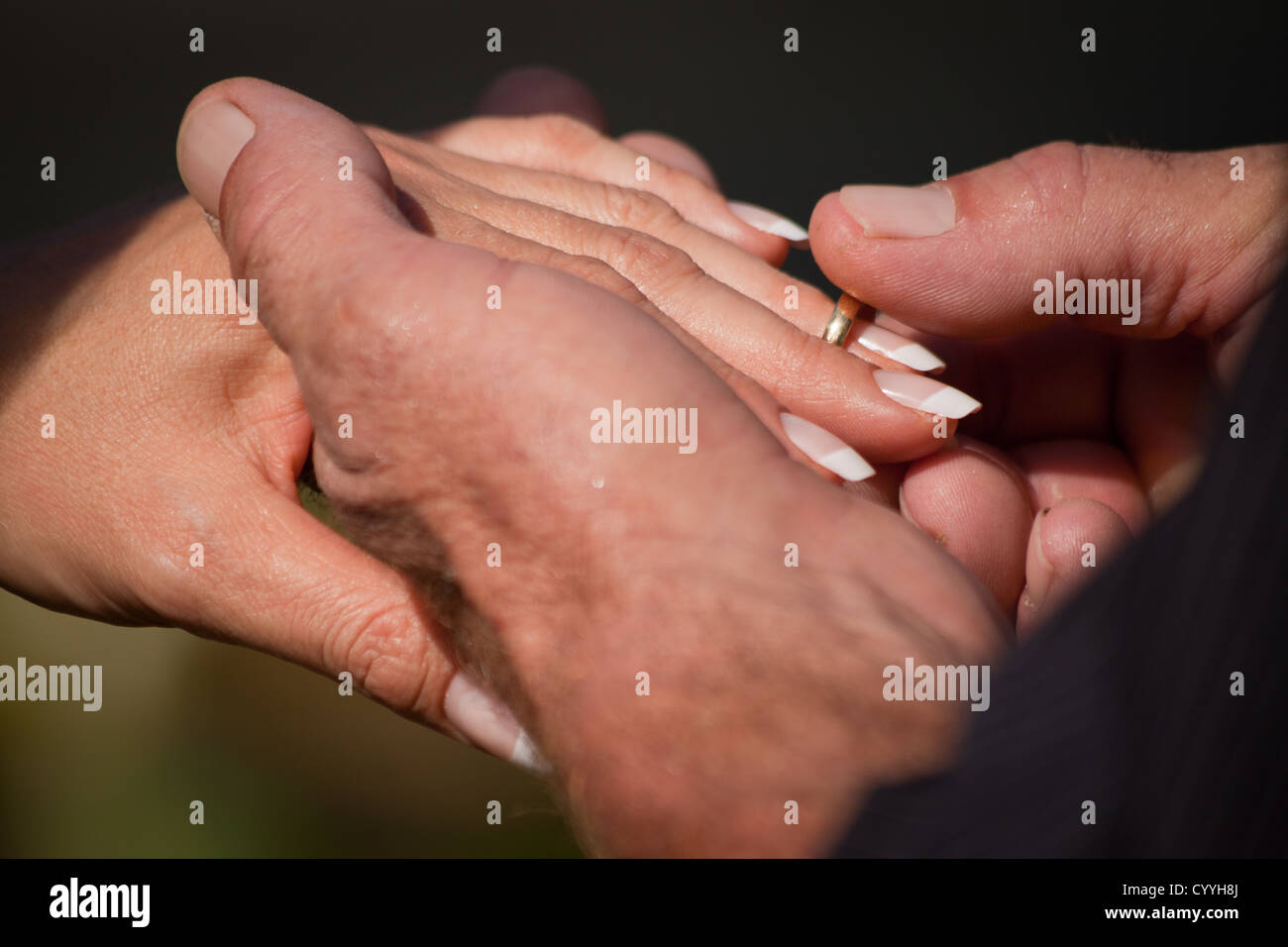 Un primo piano di uno sposo di mettere l'anello sul dito spose durante una cerimonia di nozze Foto Stock