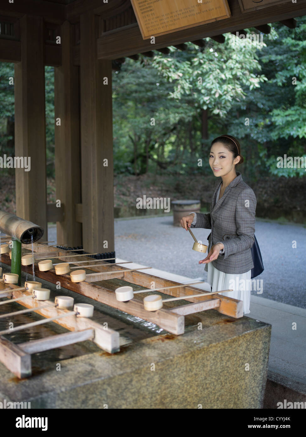 Bella giovane donna giapponese visitando Meiji Jingu, Tokyo. Presso il trogolo di purificazione (chōzuya o temizuya) Foto Stock