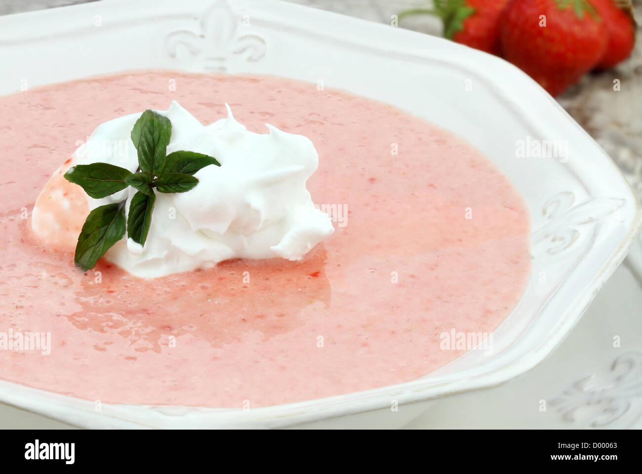 Macro di una ciotola di refrigerate zuppa di fragole, guarnita con un ciuffo di panna montata e una fresca 1 ciuffo di menta al cioccolato Foto Stock