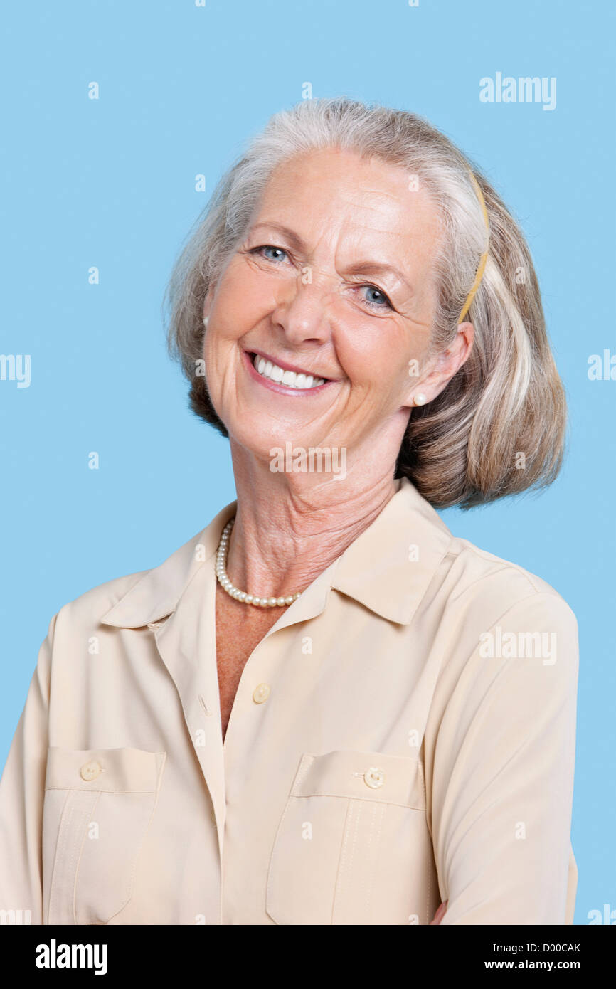 Ritratto di sorridente donna senior in casuals contro sfondo blu Foto Stock