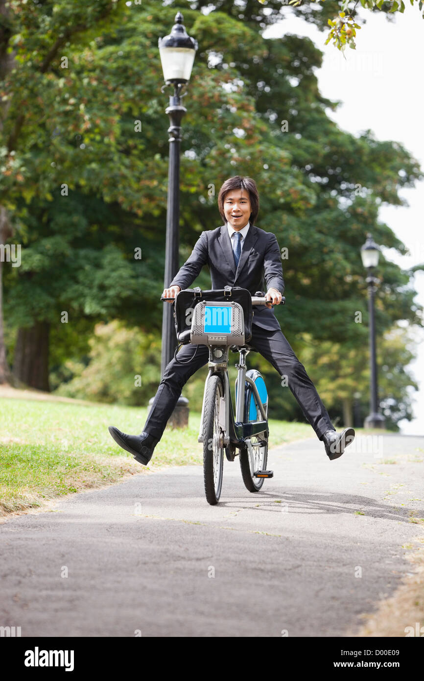 Ritratto di giovane imprenditore Bicicletta Equitazione con le gambe fuori a calci Foto Stock