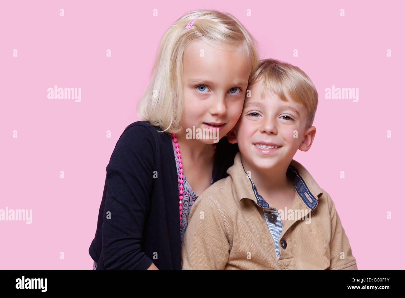 Ritratto di giovane ragazza con felice fratello su sfondo rosa Foto Stock