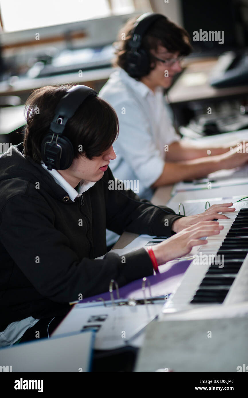 Due ragazzi adolescenti suonando piano tastiere in una sesta forma di musica lezione di classe ad un secondario completo scuola, Wales UK Foto Stock