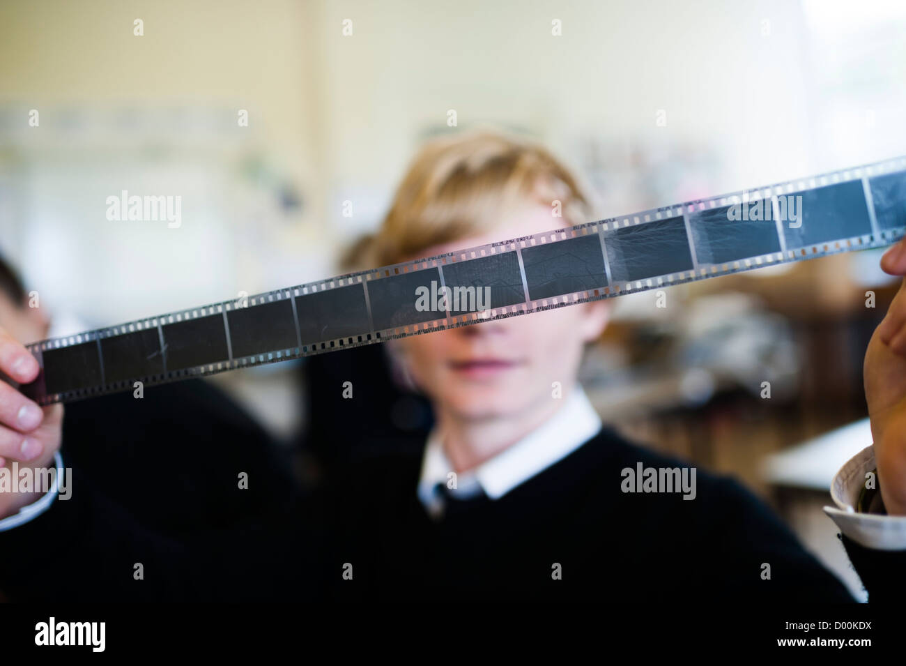 Un sesto livello di formare gli studenti studiando fotografia a un secondario completo scuola Wales UK - boy holding striscia di 35mm di negativi Foto Stock