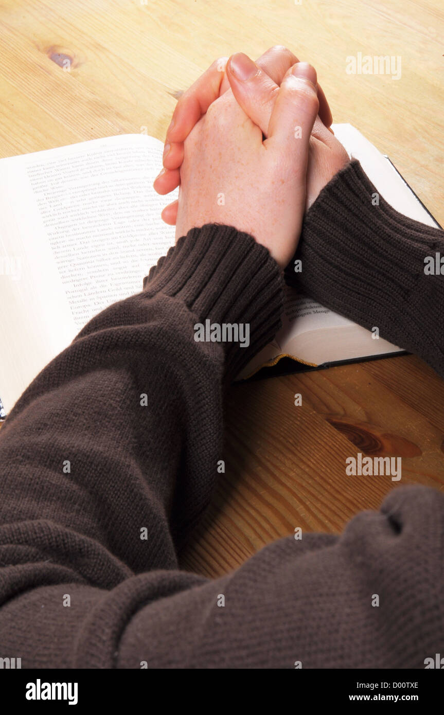 Pregando le mani e il libro che mostra la religione cristiana nozione Foto Stock