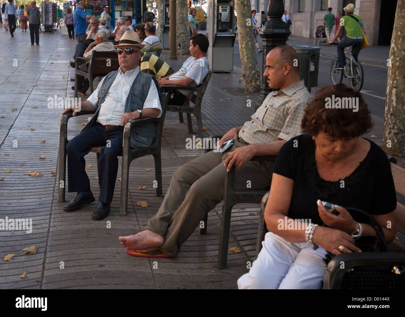Turisti stanchi e agli acquirenti di prendere una pausa sulle sedi pubbliche a Las Ramblas, Barcelona Foto Stock