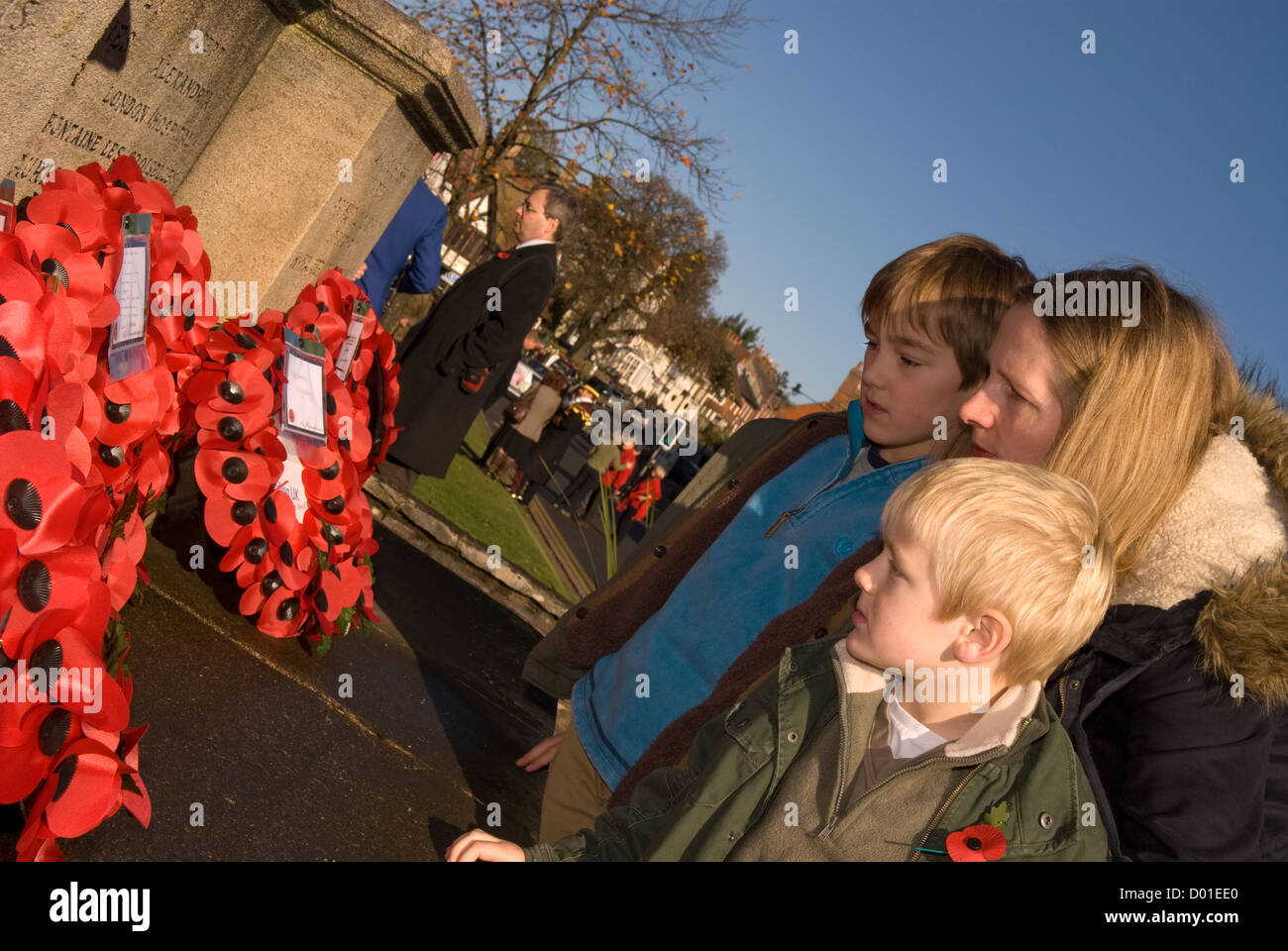 Madre e figli che stanno curiosando ghirlande a sinistra al memorial sul ricordo domenica, High Street, Haslemere, Surrey, Regno Unito. 11.11.2012. Foto Stock