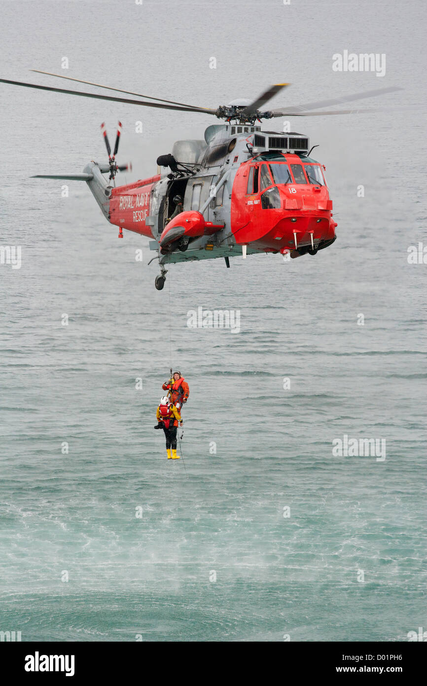 Un uomo di vino che viene abbassato da un elicottero Search and Rescue al largo di Newquay, Cornovaglia, S W Inghilterra, durante un'esercitazione di salvataggio in mare. Foto Stock