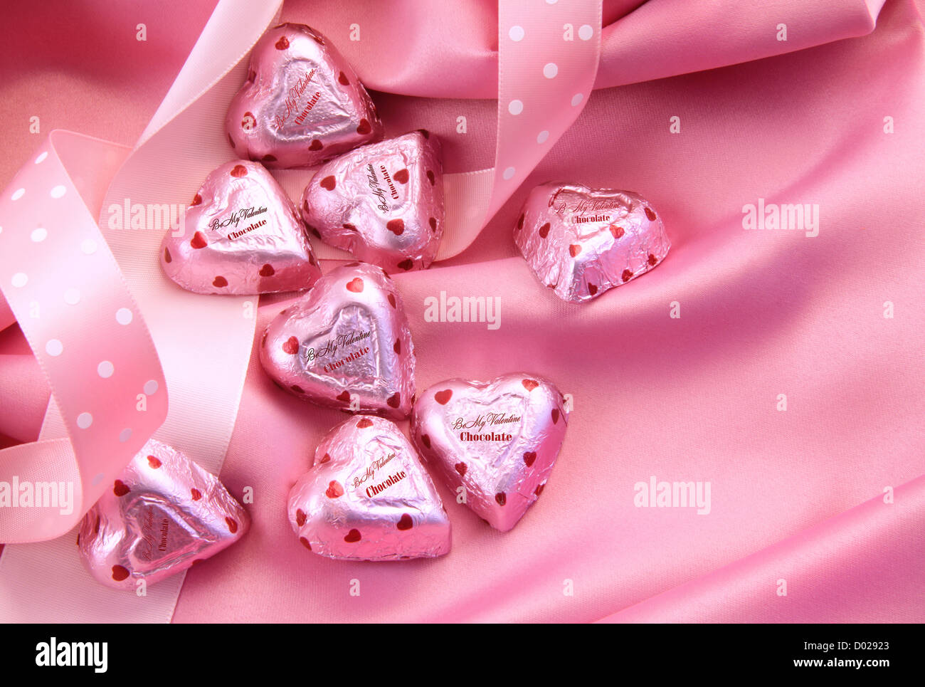 San Valentino Cuori di cioccolato su raso rosa con nastro Foto Stock