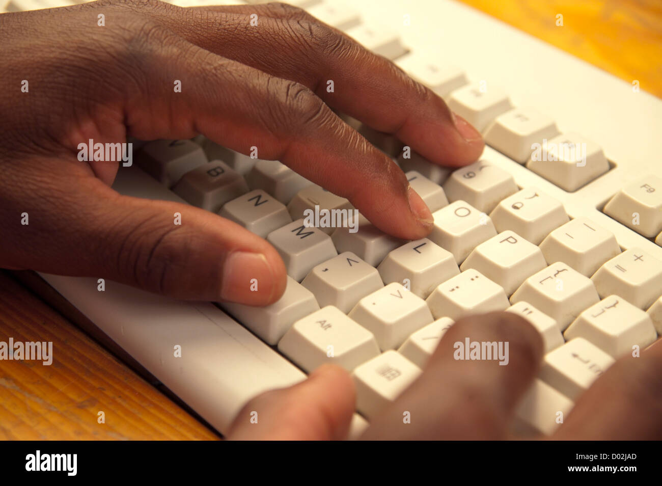 L'uomo africano con le mani in mano la digitazione su grigio della tastiera del computer Foto Stock