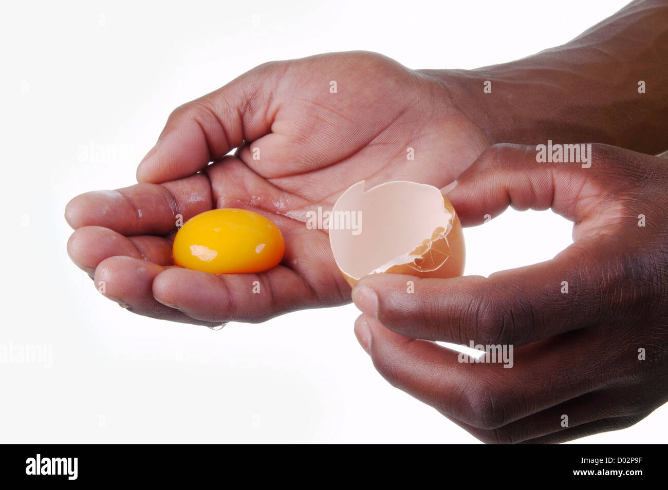 Mano azienda uovo crudo in una mano e un guscio d'uovo in un altro Foto Stock