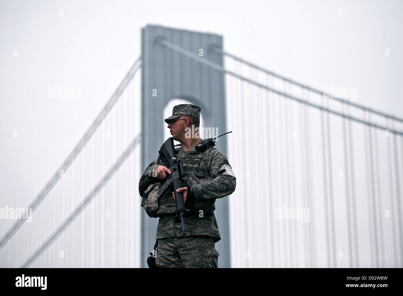 Armato di un soldato americano sta di guardia all'ombra del Verrazano-Narrows collegamento ponte di Brooklyn a Staten Island Maggio 18, 2012 a Fort Hamilton in New York City. Foto Stock