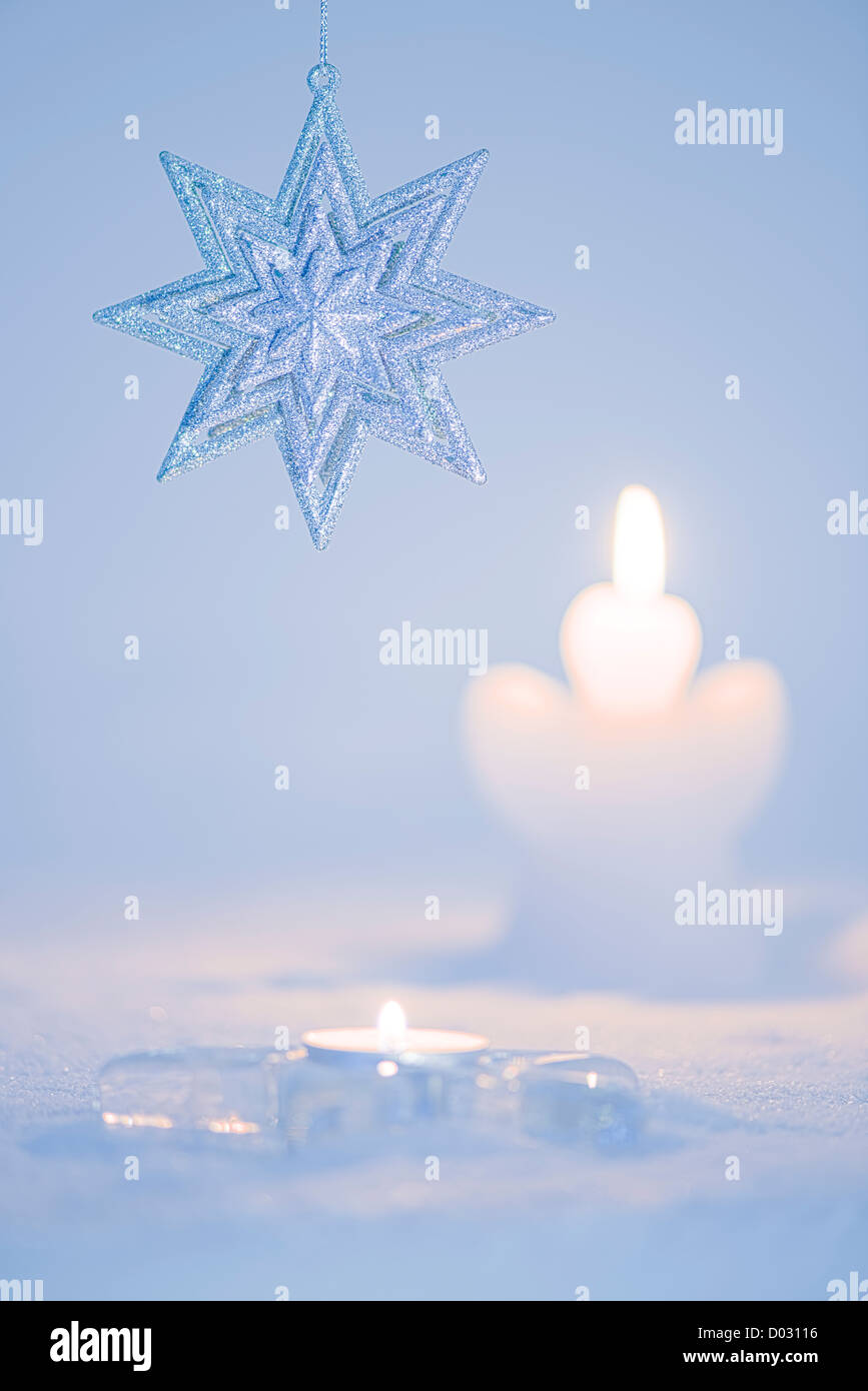 Glitter star. Decorazione per albero di Natale sulla luce blu sullo sfondo innevato. Romantica a lume di candela. Foto Stock