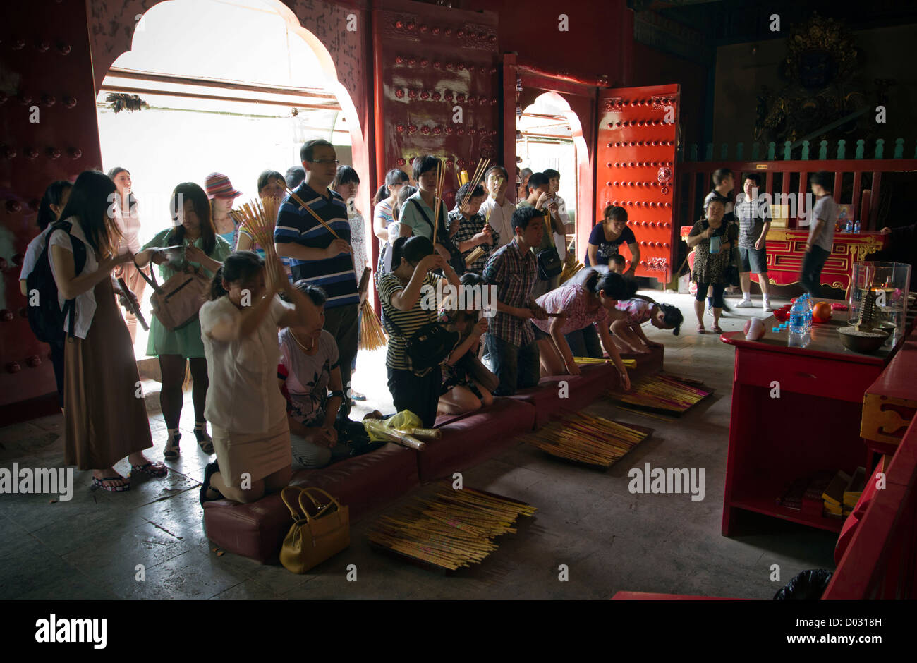 Donne e uomini bruciando incenso e pregando all interno del santuario del tempio Lama a Pechino in Cina. Foto Stock