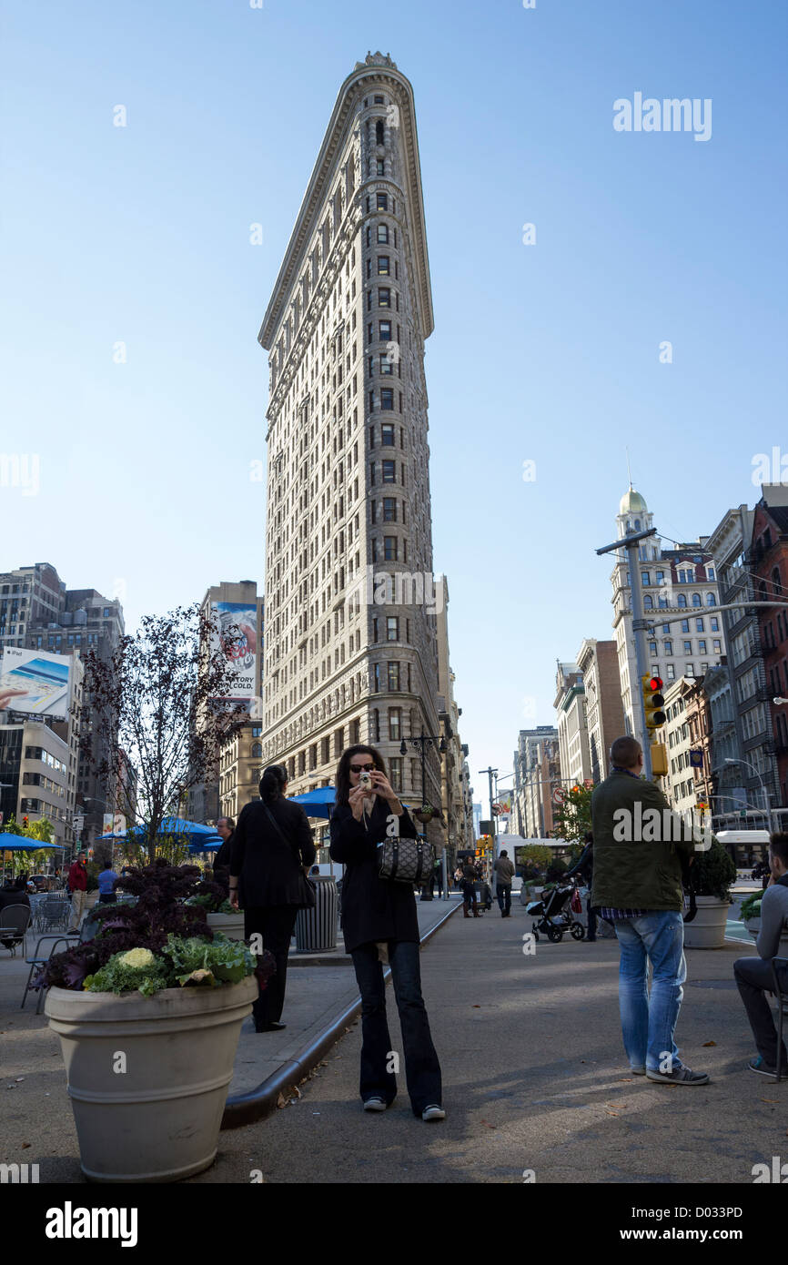 Donna di scattare una foto di fronte al Flatiron Building di New York Foto Stock