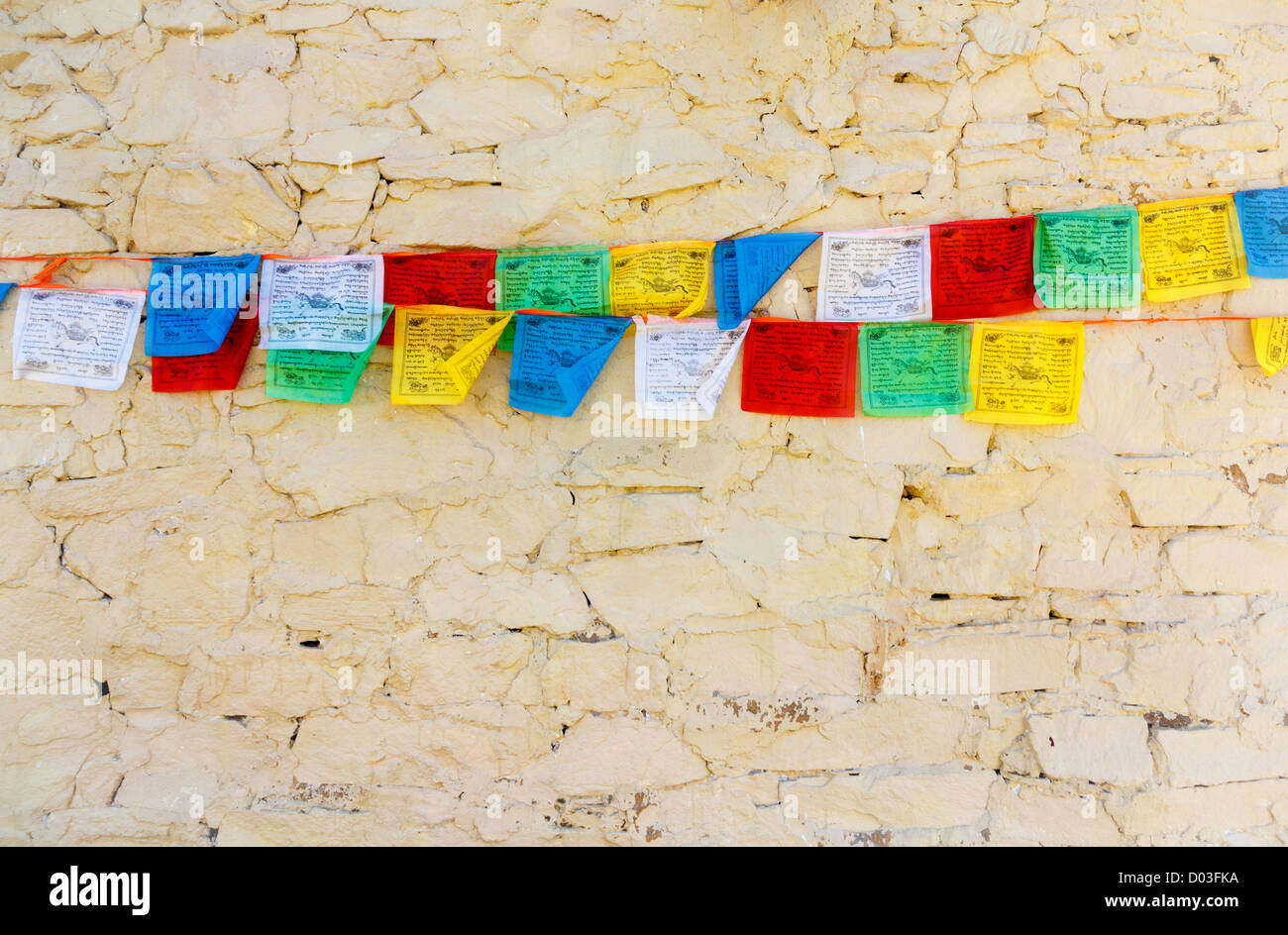 Buddista preghiera tibetano bandiere contro il muro di pietra Foto Stock