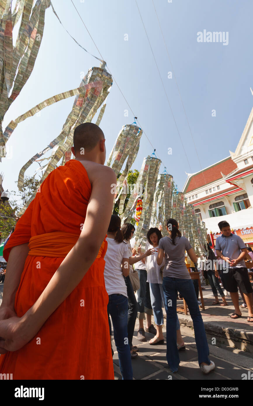 Monaco guarda le donazioni di denaro a una stringa nel tempio di Wat Arun a Bangkok, in Thailandia Foto Stock