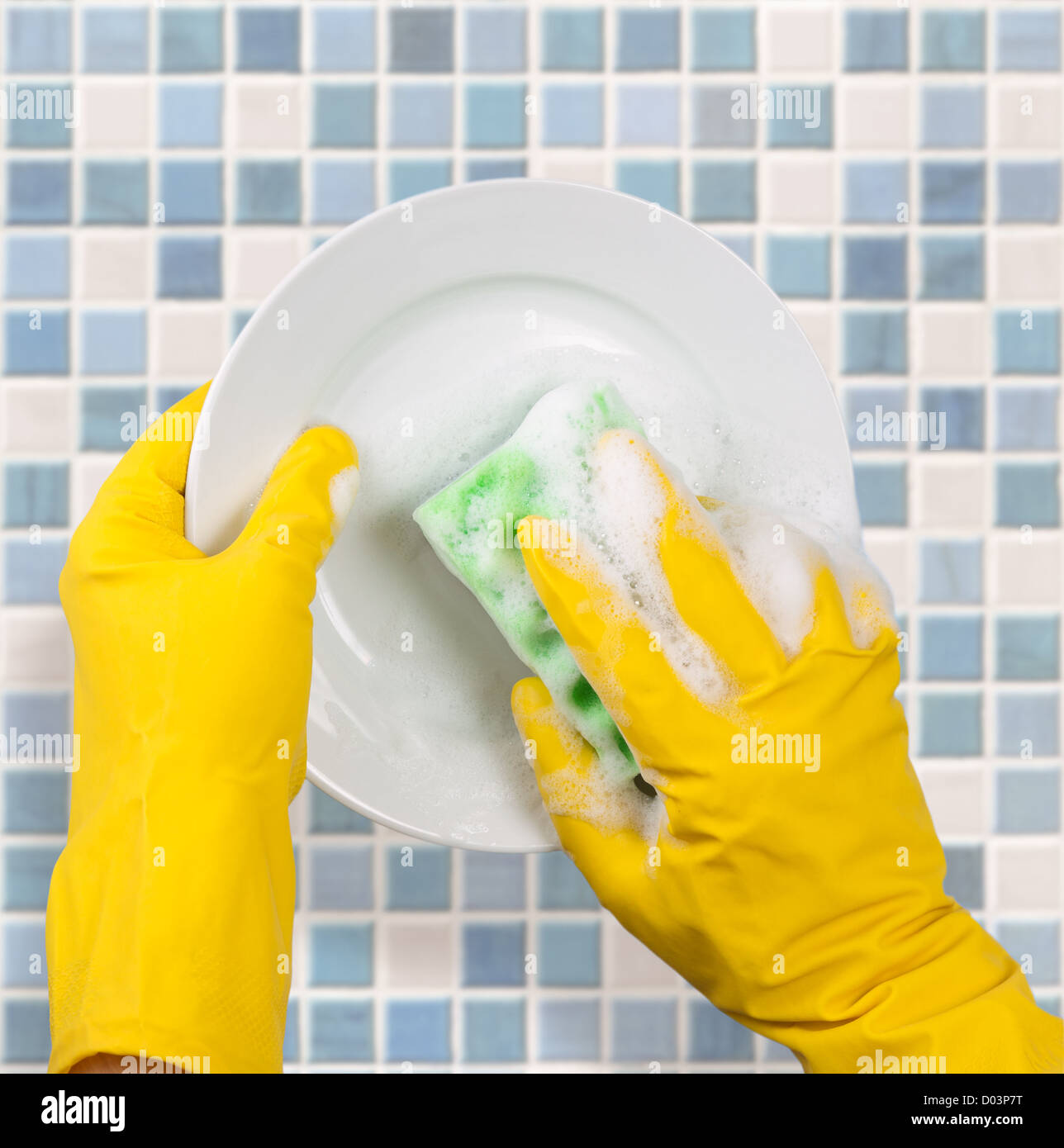 Mani in Guanti gialli piatto di lavaggio sulla piastrella sfondo da cucina  Foto stock - Alamy