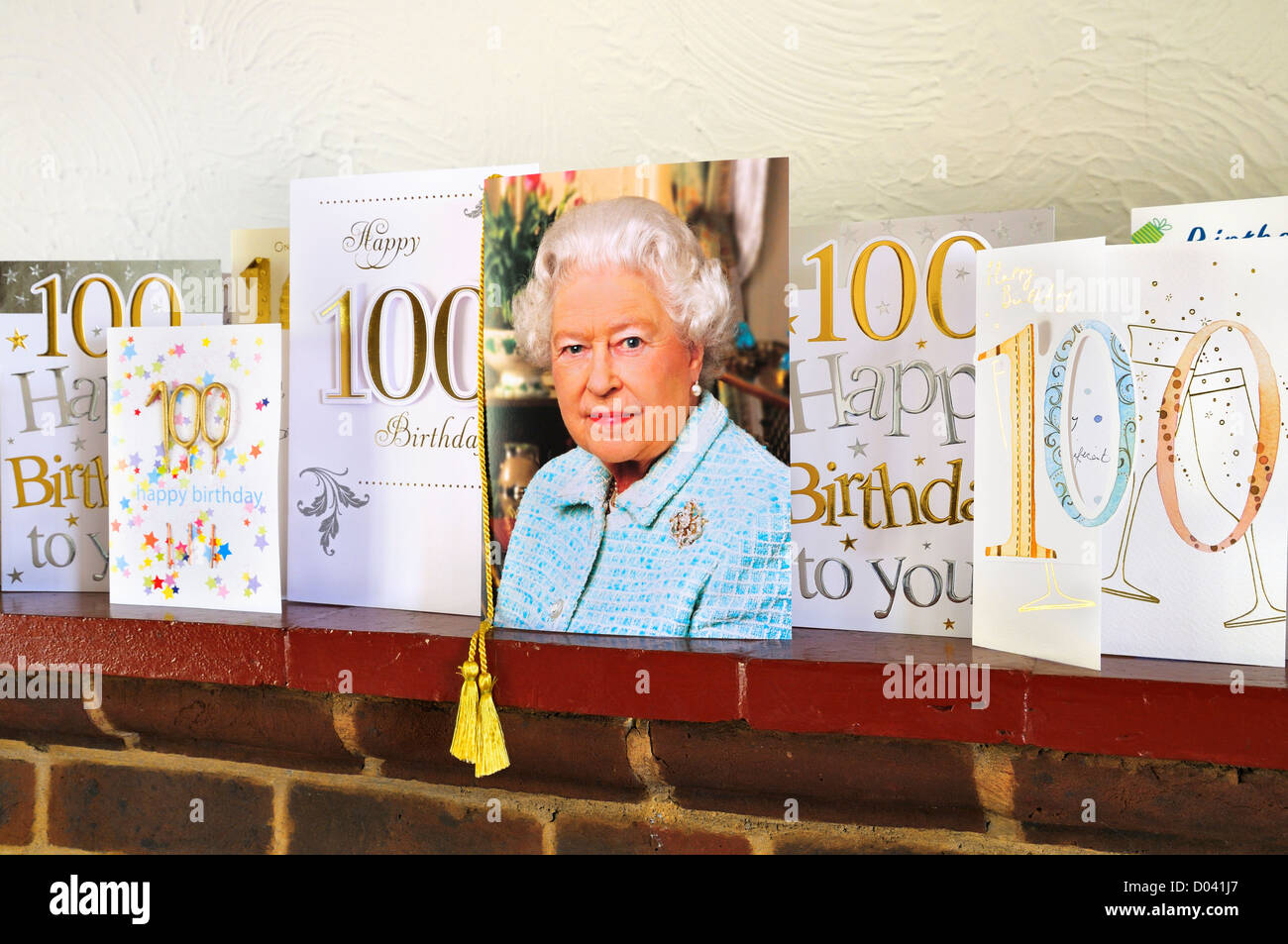 Centesimo cartoline di compleanno a fianco di una scheda personalizzata da parte di Sua Maestà la Regina Elisabetta II su un mantelpiece Foto Stock