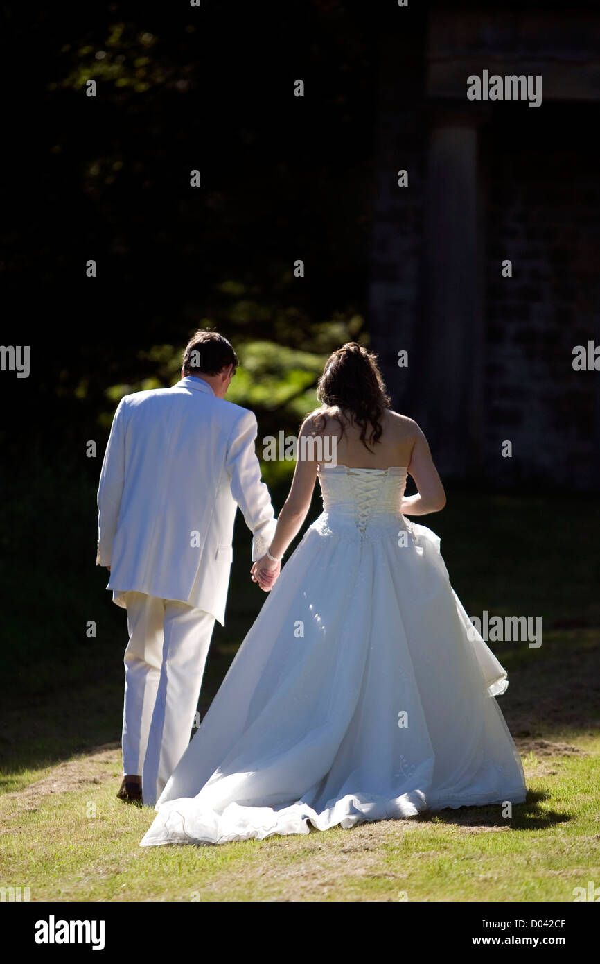 Sposa giovane a piedi largo in distanza insieme mano nella mano Foto Stock