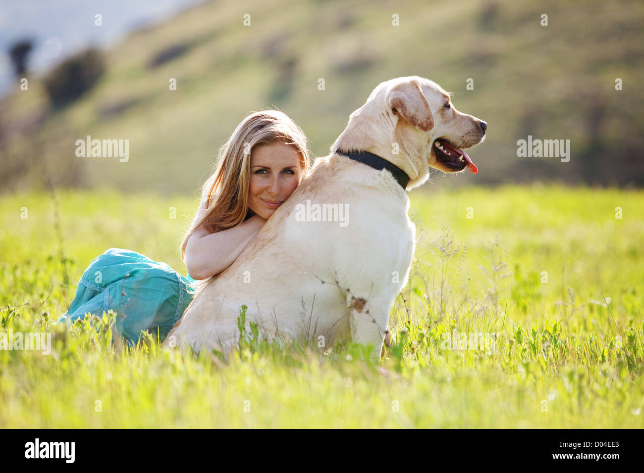 Giovane donna con ger cane in appoggio in corrispondenza del campo verde Foto Stock