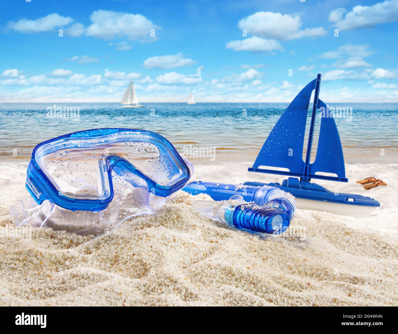 Gli occhiali di protezione e il giocattolo in barca a vela in sabbia in spiaggia scena Foto Stock