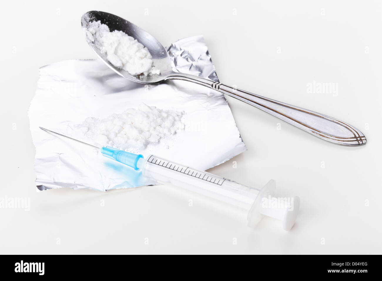 La siringa e la cocaina sulla lamina, primo piano su bianco Foto Stock
