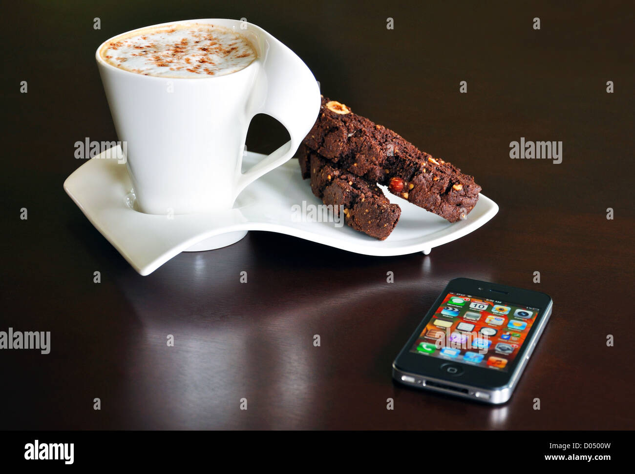 Caffè con spuma di cioccolato e nocciola biscottis in fantasia set di tazza e iPhone accanto a loro Foto Stock