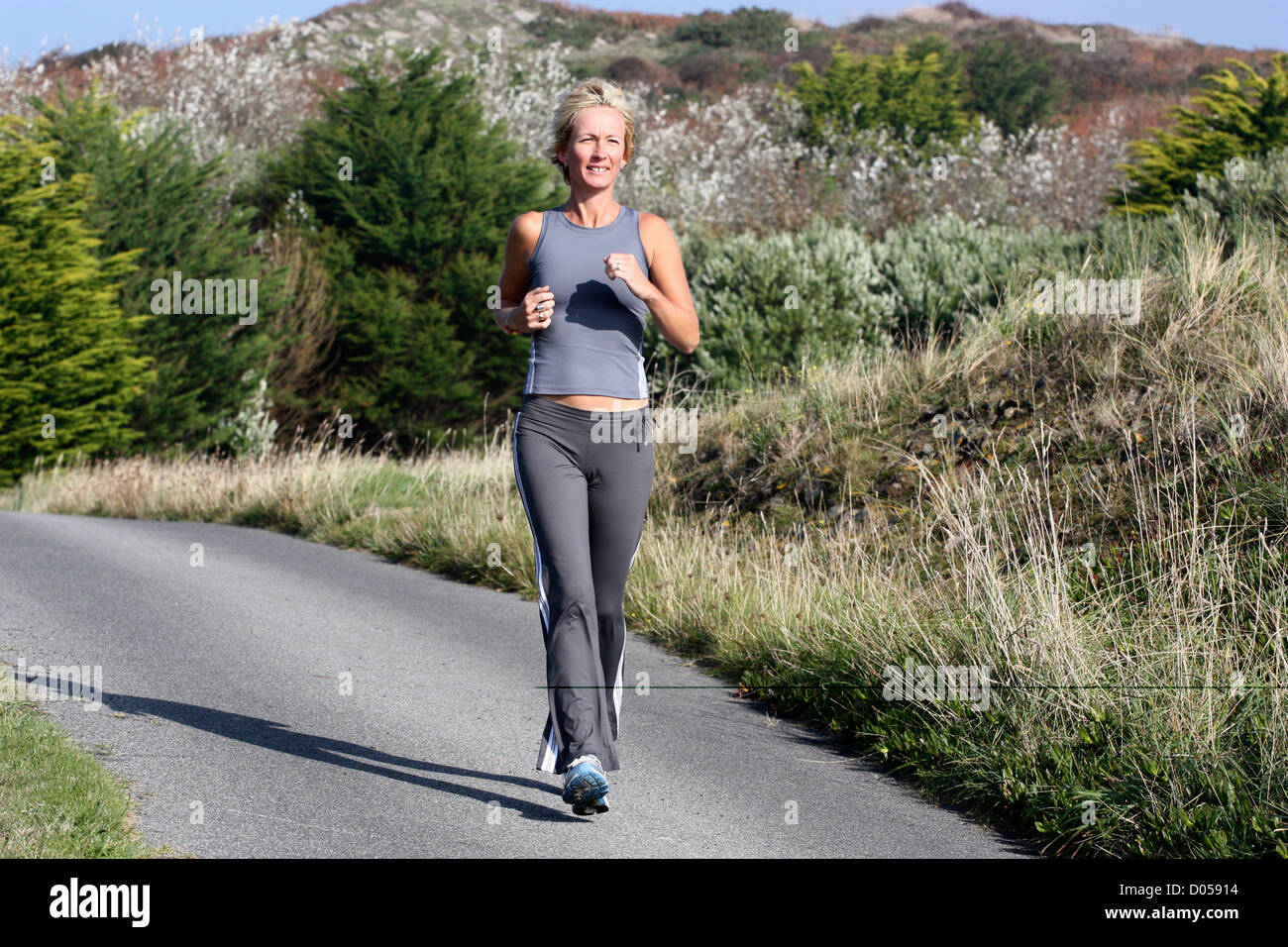 Donna bionda all'esterno. Jogging lungo la strada di campagna. Foto Stock