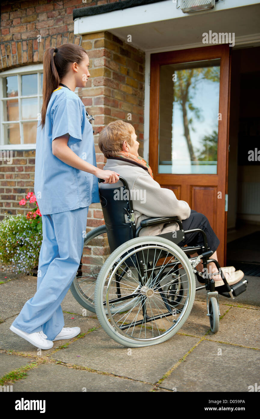 Infermiere/medici spingendo anziani paziente di sesso femminile in una sedia a rotelle verso l ingresso dell ospedale o casa di cura. Foto Stock