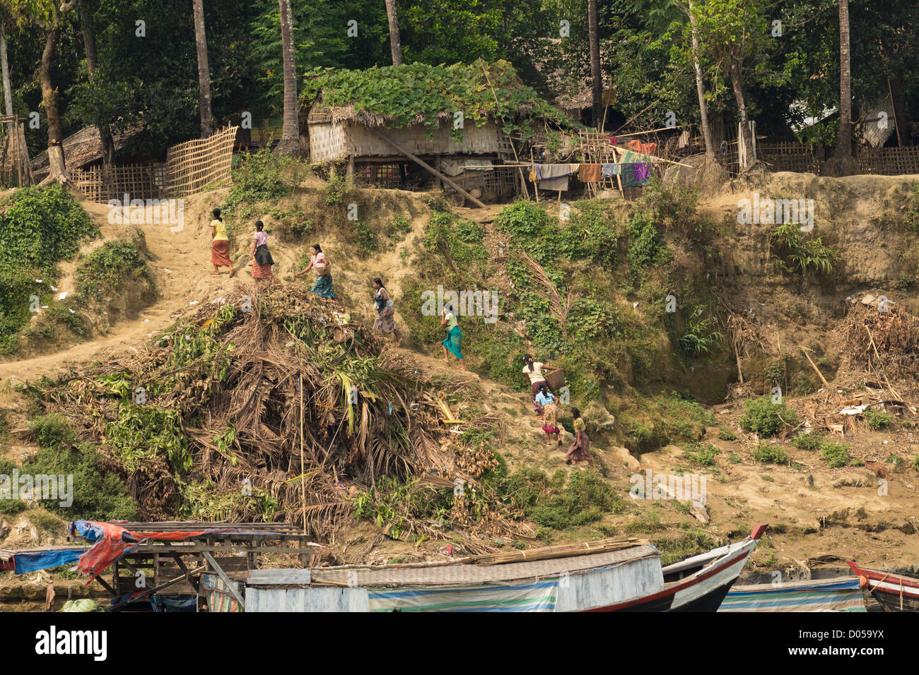 Una linea di persone di affrontare una salita con forte riverbank sul fiume Laymyo. Foto Stock