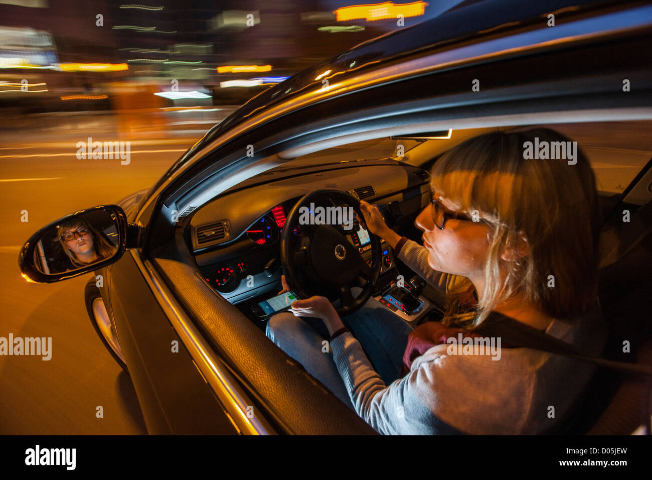 La donna è alla guida di un'auto. Utilizzando un telefono cellulare. Non è consentito durante la guida di un'auto. Foto Stock