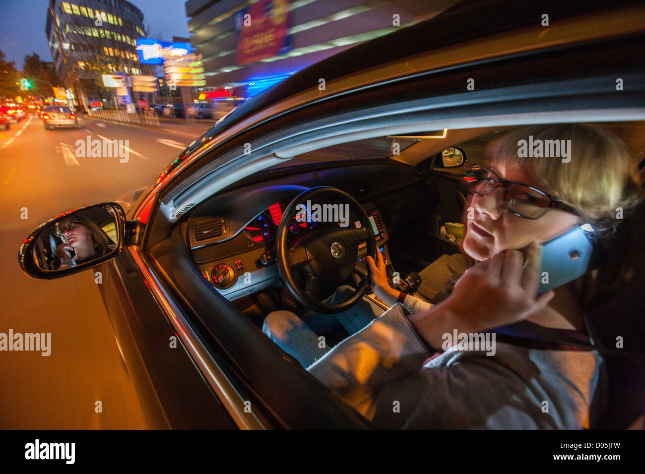 La donna è alla guida di un'auto. Utilizzando un telefono cellulare. Non è consentito durante la guida di un'auto. Foto Stock