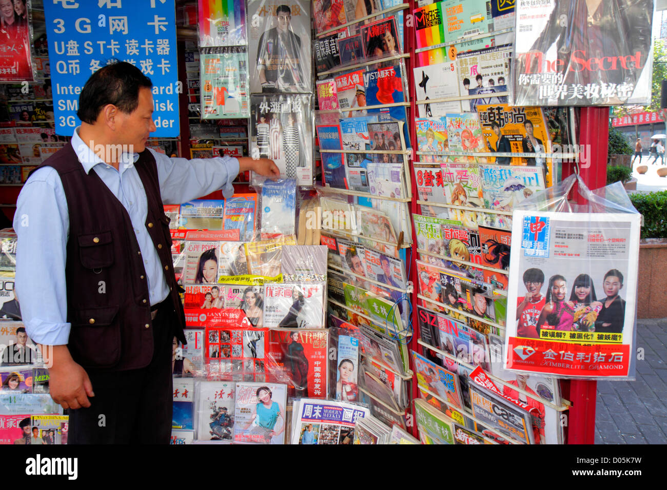 Shanghai Cina, quartiere cinese Huangpu, Jiangxi Road, uomo asiatico uomini maschio adulti, cinese Mandarin simboli, hanzi, edicola, riviste, case espositore s. Foto Stock