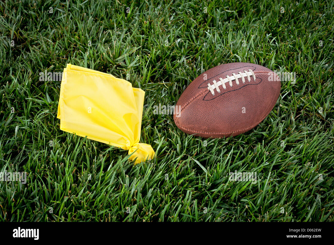 Un giallo bandiera di penalità e il calcio giacere immobile su un campo da gioco. Foto Stock
