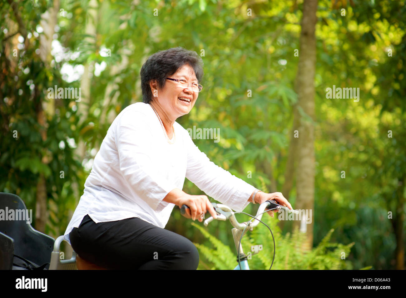 60s senior donna asiatica equitazione sulla bicicletta all'aperto con grande divertimento Foto Stock