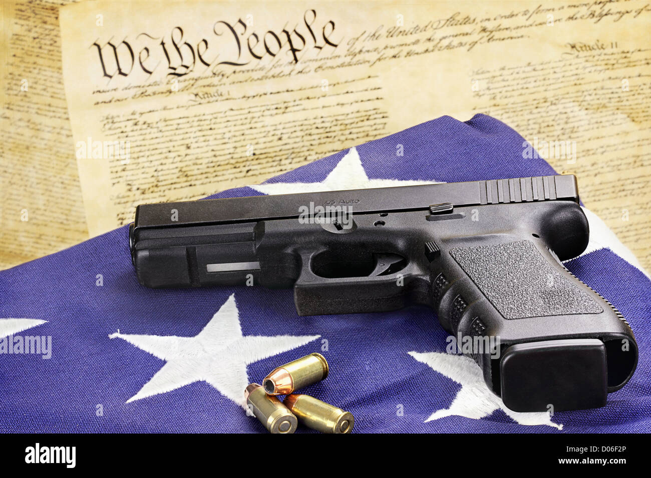 Un 45 pistola calibro e le munizioni in appoggio su una bandiera ripiegata contro la costituzione degli Stati Uniti. Foto Stock
