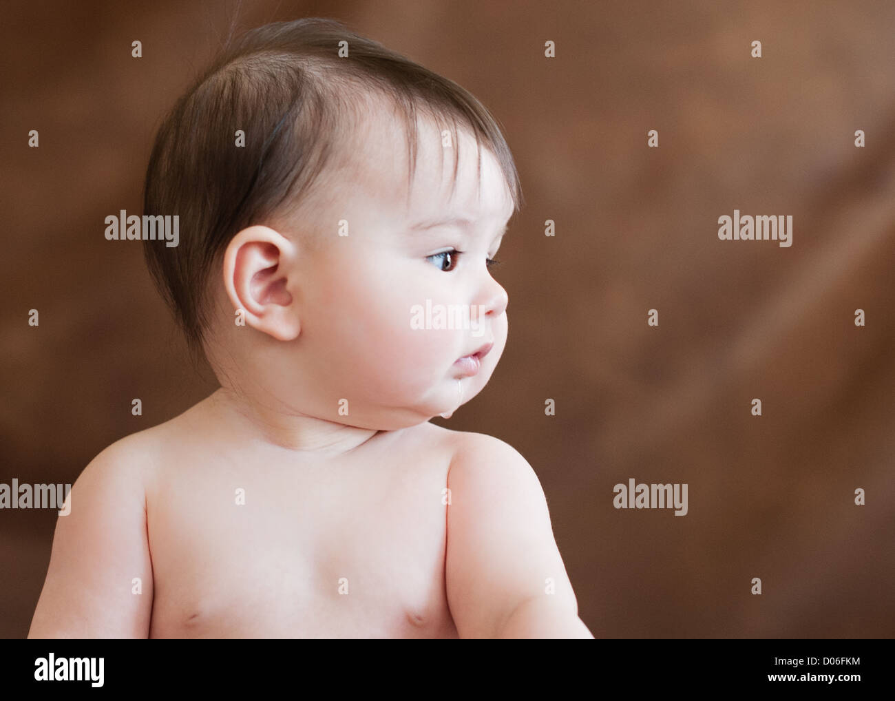 Baby girl cerca lateralmente con sbavature sul suo mento Foto stock - Alamy