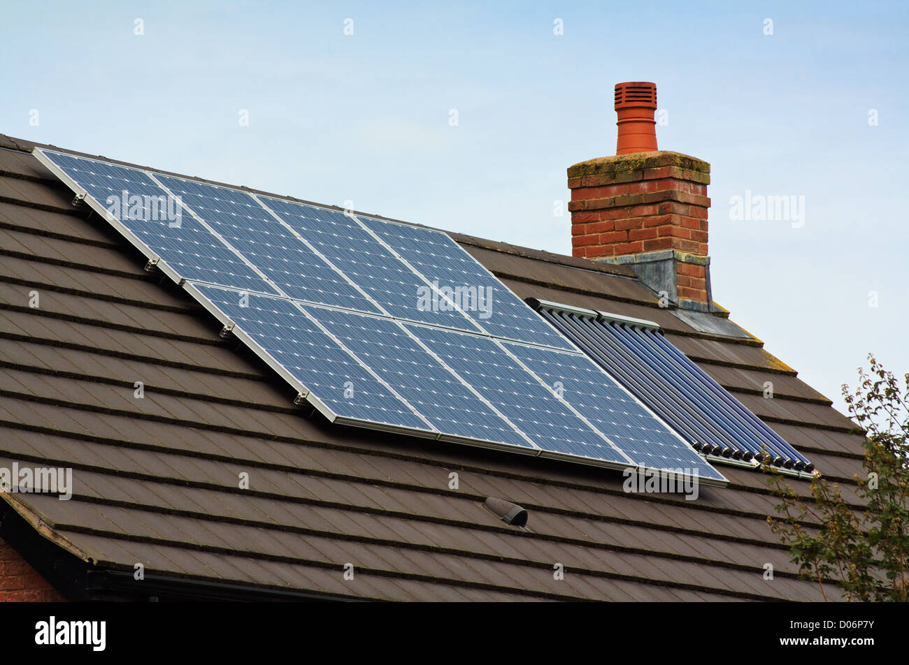 Solare fotovoltaico e riscaldamento centrale dei pannelli sul tetto di tegole di casa residenziale Foto Stock