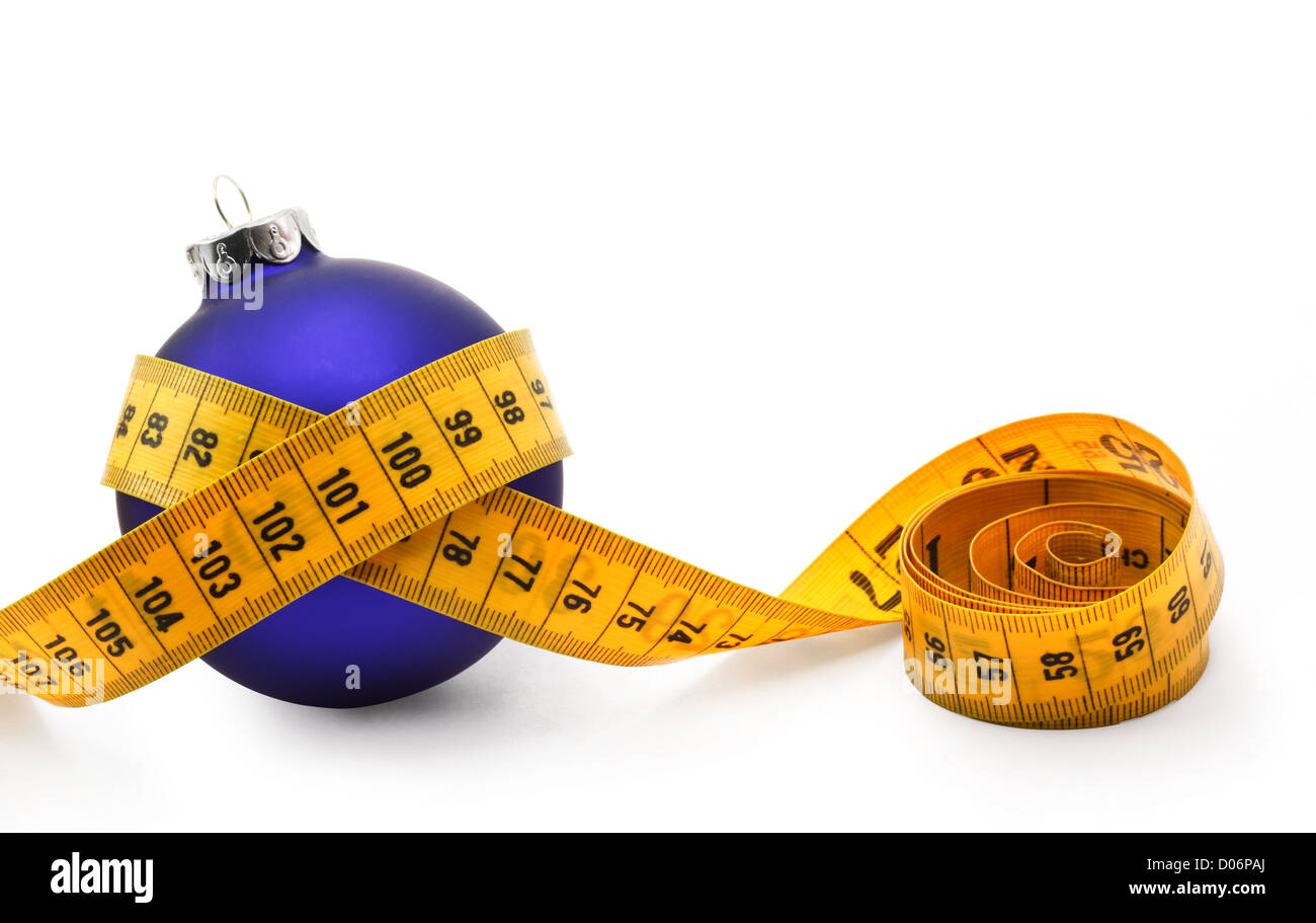 Metro a nastro attorno ad un concetto di pallina che simboleggiano il Natale guadagno di peso da mangiare troppo cibo. Foto Stock