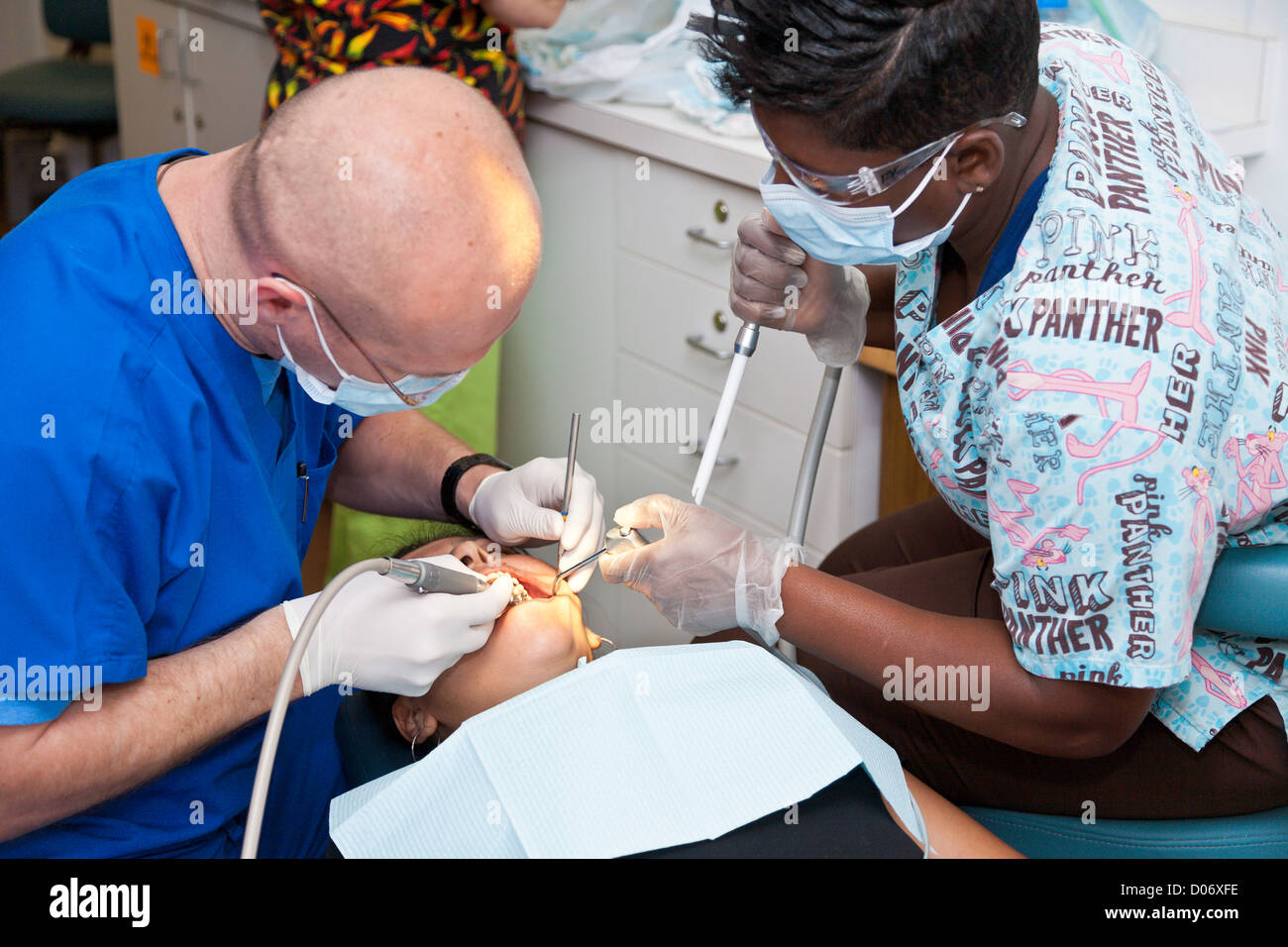 Maschio bianco dentista volontari e assistente forniscono servizi per il nero donna attraverso la missione sorrisi clinica mobile a Tampa, FL Foto Stock