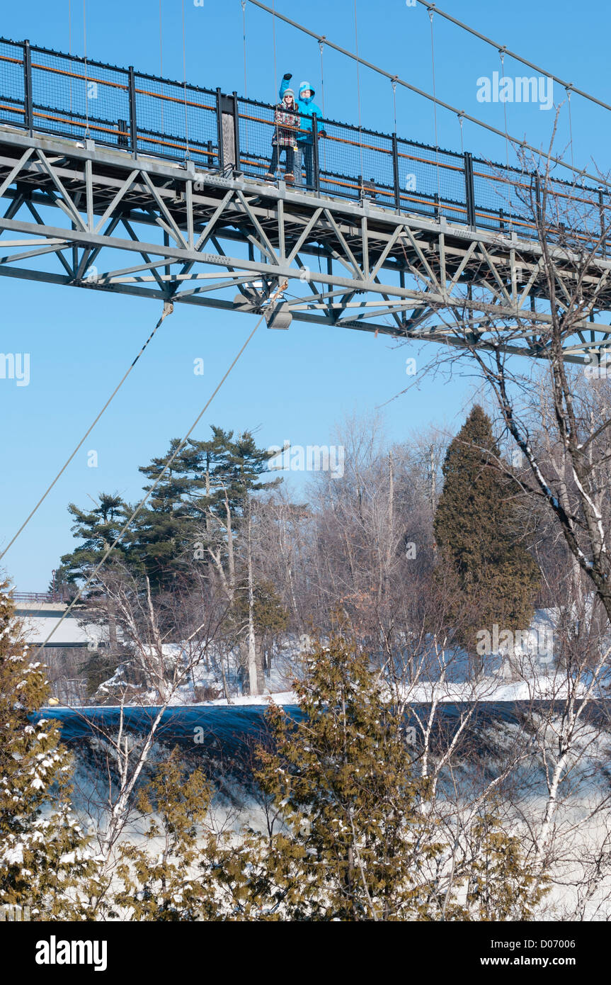 Padre e figlia in inverno stare in cima al ponte di Montmorency cade in Québec in Canada con il fiume e il ghiaccio e la neve qui di seguito. Foto Stock