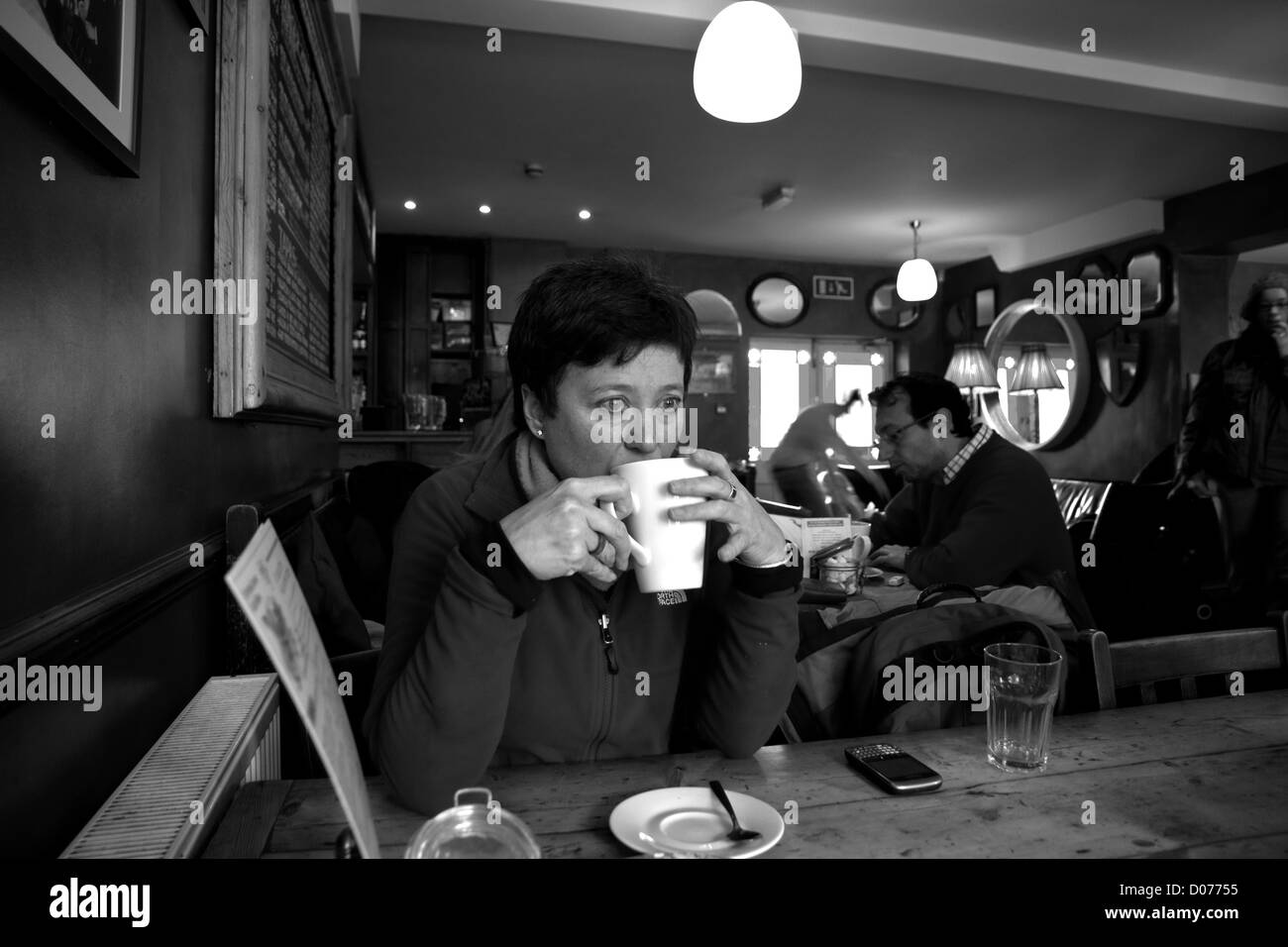 Una donna che beve caffè in un bar/caffè Foto Stock