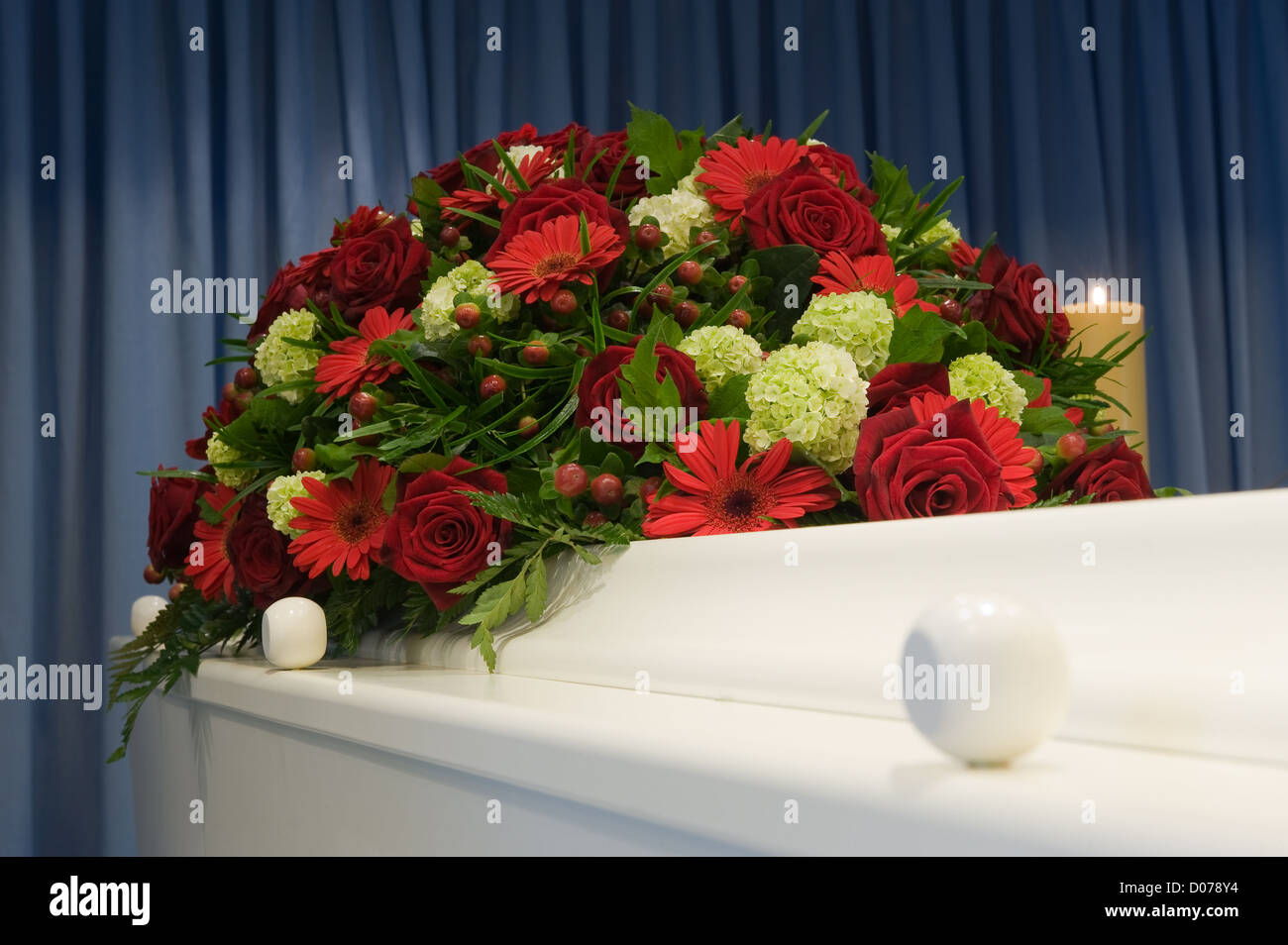 Una bara bianca in una camera mortuaria con una composizione floreale Foto Stock