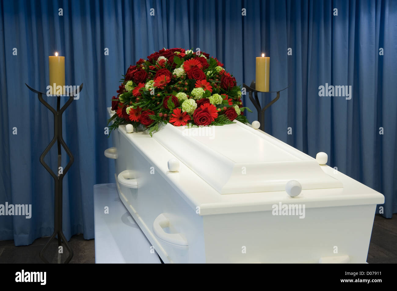 Una bara bianca in una camera mortuaria con una composizione floreale Foto Stock