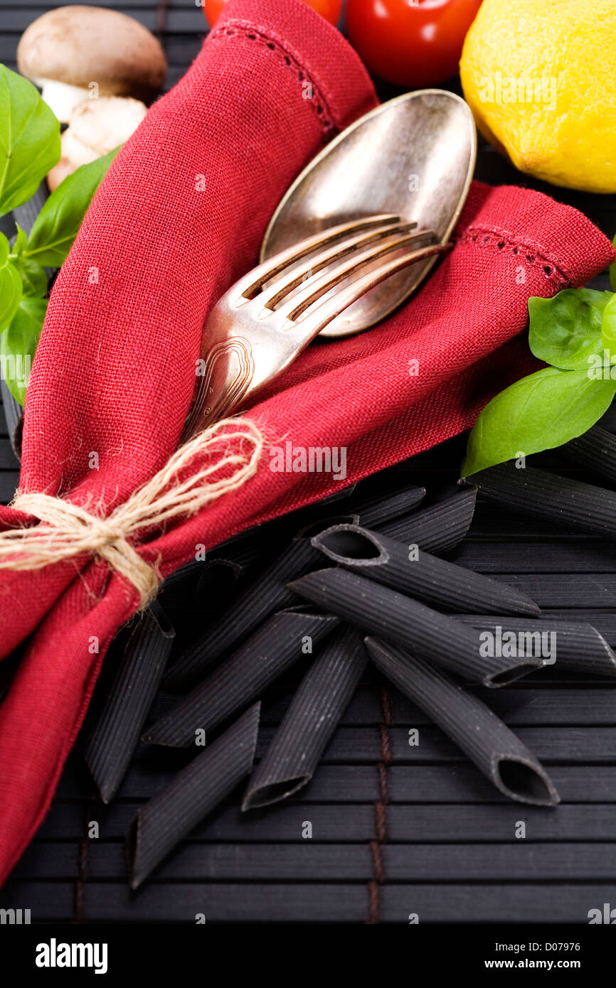 Cucchiaio e forchetta, igienico e ingredienti per la pasta (penne, basilico, funghi, pomodoro, limone) Foto Stock